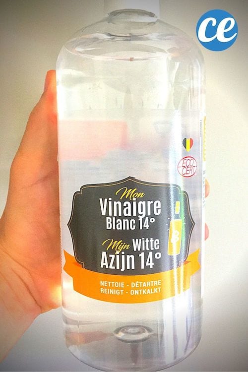 Une bouteille de vinaigre blanc blanche transparente tenue dans la main