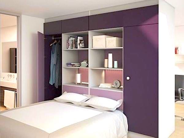 Un petit dressing de couleur violet posé contre un mur qui fait aussi tête de lit