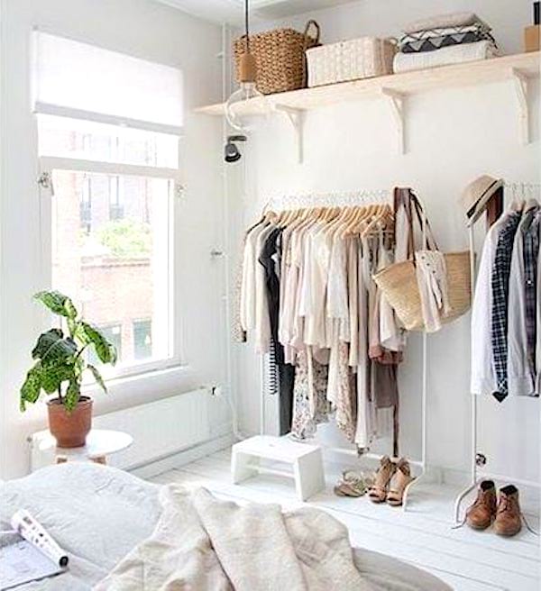 Un petite dressing fait avec des portants dans une pièce blanche d'appartement