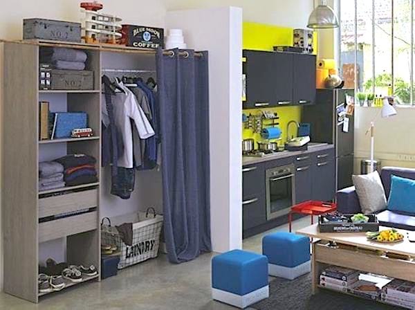 Un petit dressing fait avec une étagère et un rideau dans un studio
