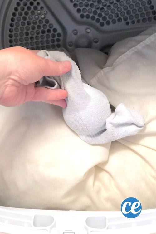 Une balle de tennis dans une chaussette est placé dans un sèche-linge avec un oreiller