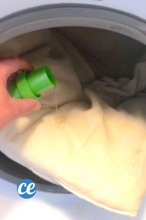 De la lessive liquide versée sur un oreiller jauni dans une machine à laver