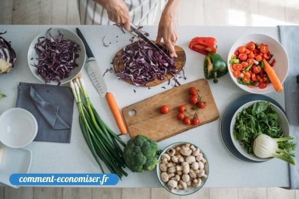 Une femme qui coupe les légumes sur un plan de travail.