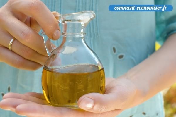 Une femme qui tient une bouteille d'huile d'olive dans une bouteille en verre.