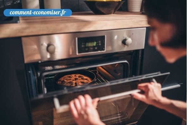 Une femme qui vérifie la cuisson d’un gâteau en ouvrant le porte du four.