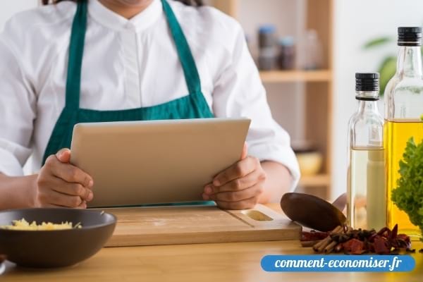 Une femme qui lit une recette sur une tablette dans une cuisine.