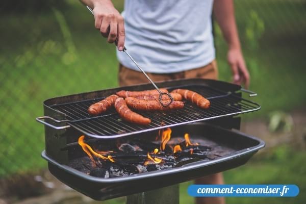 Un homme qui fait griller des saucisses sur un barbecue.