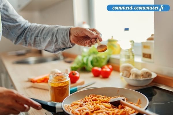 Une main qui ajoute des épices pendant la cuisson d'un plat.