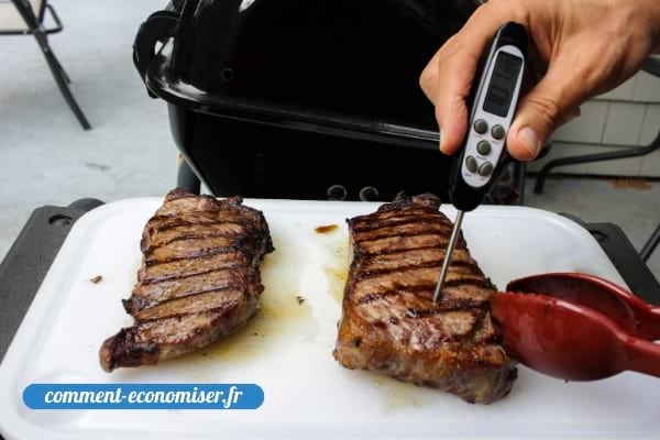 Une main qui vérifie la cuisson de la viande avec un thermomètre.