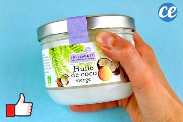 Un pot d'huile de coco dans la main sur fond bleu
