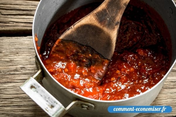 Une cuillère en bois dans une casserole de sauce tomate.