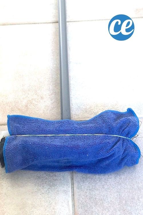 un balai entouré d'un chiffon microfibre bleu tenu avec un élastique pour nettoyer facilement les plinthes