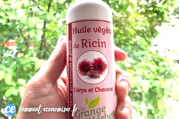Une main qui tient une bouteille d'huile de ricin.