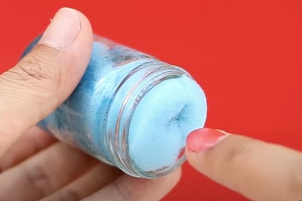 Éponge bleue dans un petit bocal utilisée pour enlever le vernis à ongles