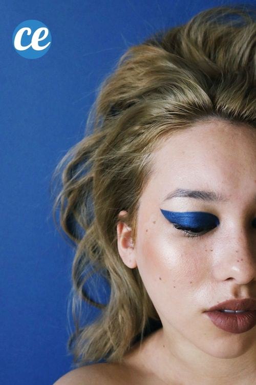 Une jeune femme blonde avec une bouche très maquillée pulpeuse et du fard à paupières bleu