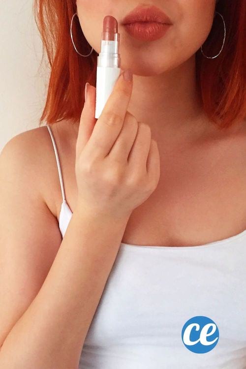 Une jeune femme avec une bouche pulpeuse et un rouge à lèvres dans les mains