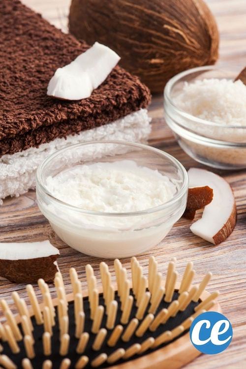Un masque à l'huile de coco  pour cheveux posé sur une table avec une brosse et des serviettes marron