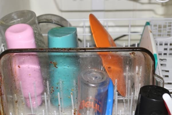 Des verres et un plat graisseux très sale dans lave vaisselle