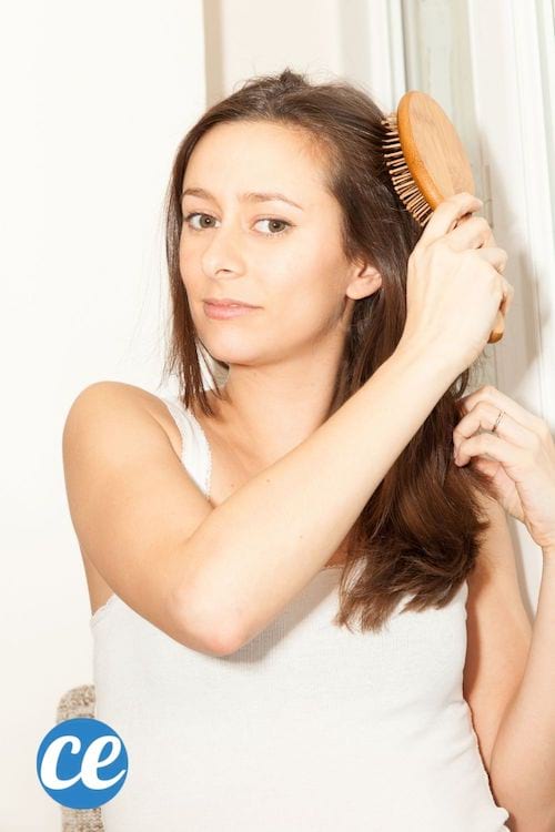 Une femme en débardeur se brosse les cheveux avec une brosse à picots