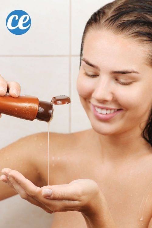 Une jeune femme verse du shampoing dans sa main