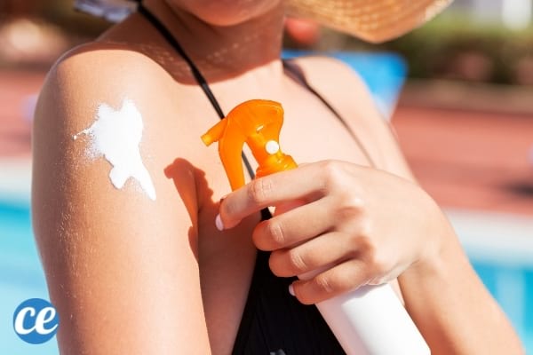 Crème solaire à spray sur la peau d'une femme en maillot de bain 