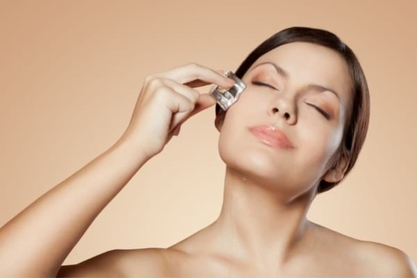 Une femme qui passe un glaçon sur le visage pour avoir un teint éclatant