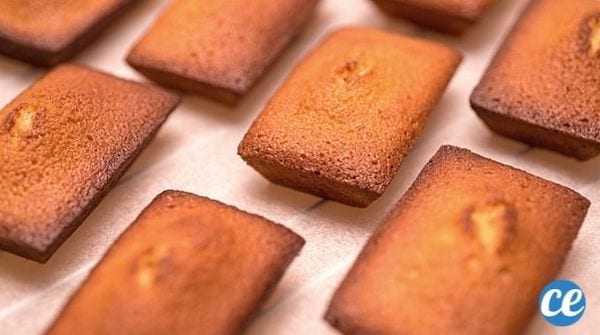 des gâteaux financiers bien dorés posés sur une grille avec une feuille de papier cuisson