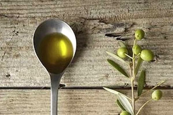 Huile d'olive dans une cuillère à café pour enlever les taches d'eau sur le bois