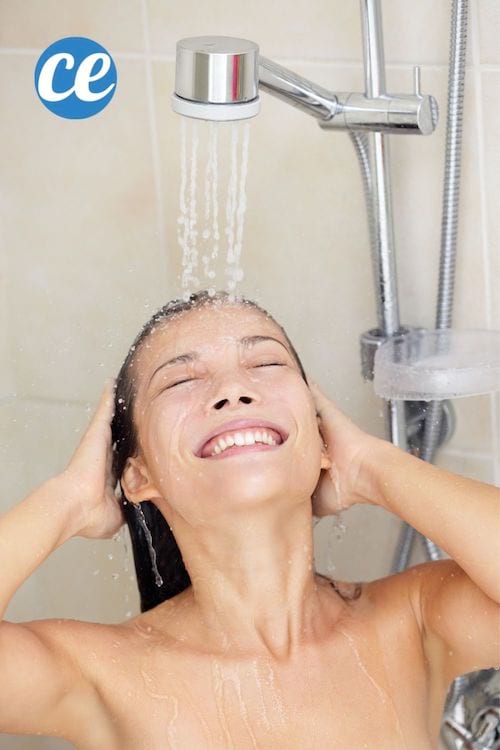 Une jeune femme se rince les cheveux sous une douche