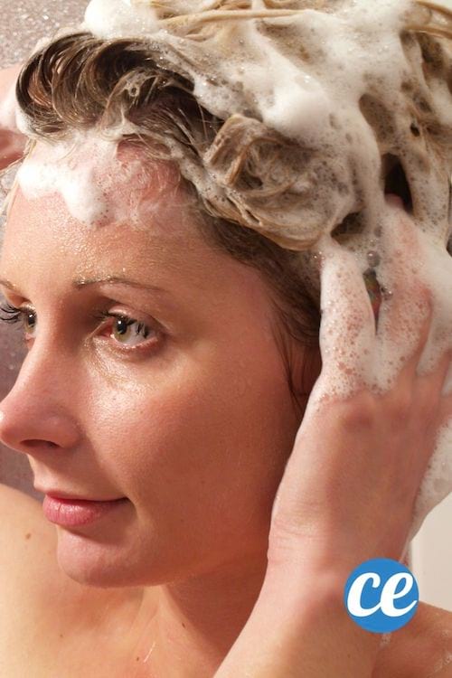 Une jeune femme fait un shampoing avec beaucoup de mousse