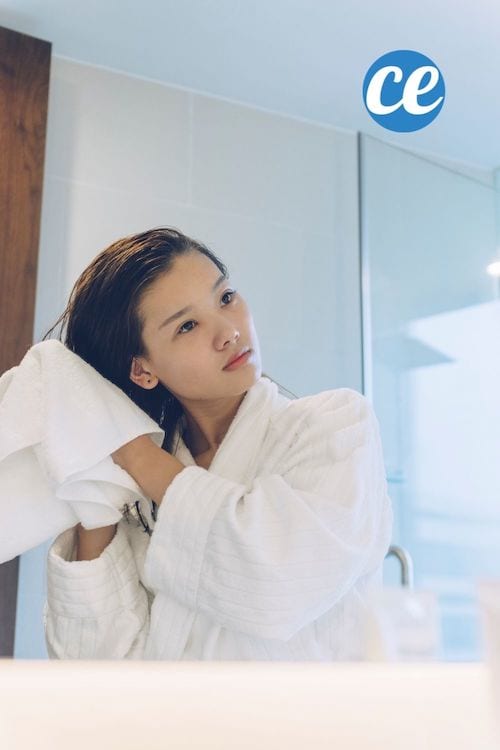 une femme se sèche les cheveux devant son miroir