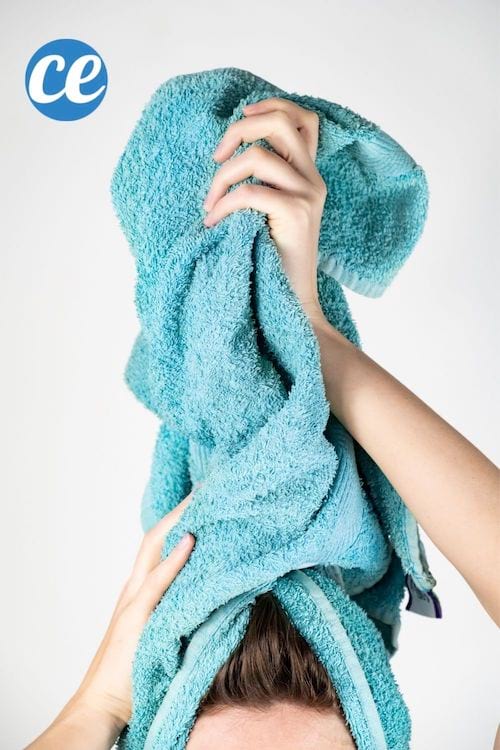 une femme séche ses cheveux avec une serviette