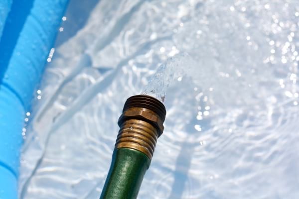 Un tuyau d'arrosage qui remplit une piscine d'eau