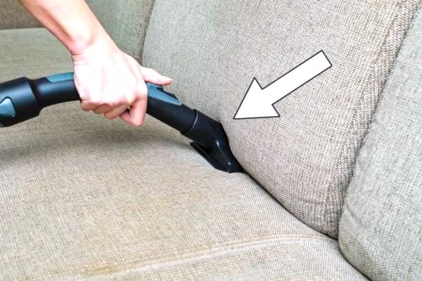 Passer l'aspirateur sur le tissu pour nettoyer un canapé en tissu qui sent mauvais.