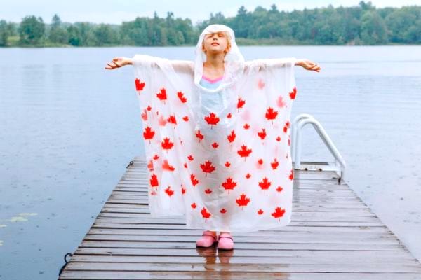 Une petite fille avec un poncho de pluie en camping.