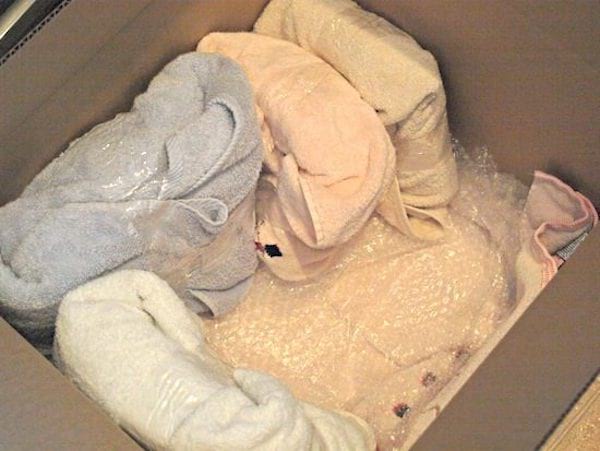 Plusieurs objets protégés par des serviettes dans des gros cartons