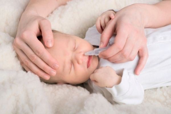 Une personne nettoie le nez d'un bébé avec du sérum physiologique