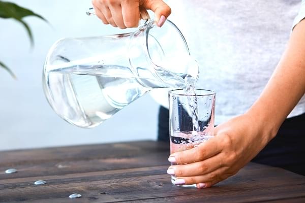 Une personne se servant de l'eau dans un verre 