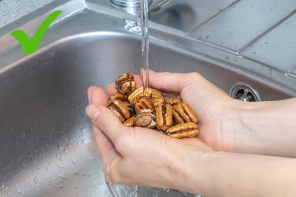 Des noix en train d'être lavées sous l'eau du robinet
