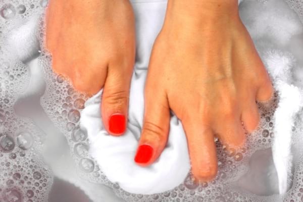 Une femme nettoyant un linge blanc dans de l'eau froide