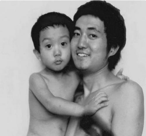 Photo en noir et blanc d'un père et de son fils torse-nu en 1988