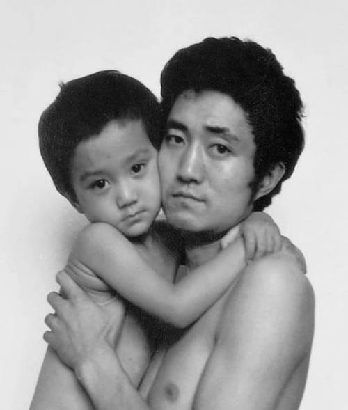 Photo en noir et blanc d'un père et de son fils torse-nu en 1989