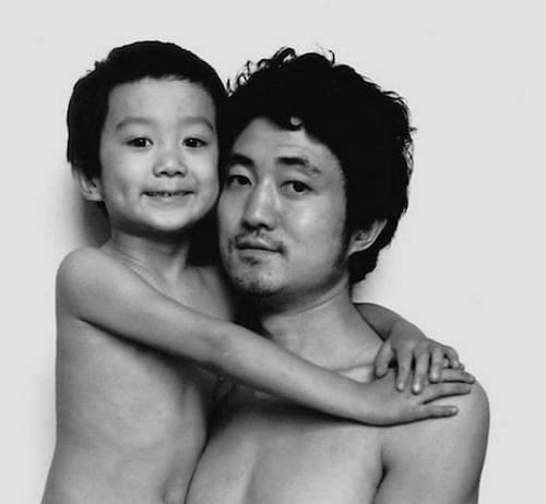 Photo en noir et blanc d'un père et de son fils torse-nu en 1991