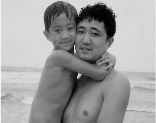 Photo en noir et blanc d'un père et de son fils torse-nu en 1992