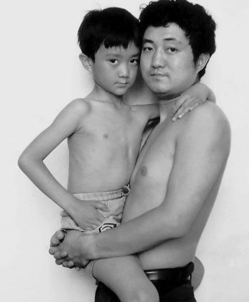 Photo en noir et blanc d'un père et de son fils torse-nu en 1993