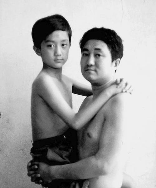 Photo en noir et blanc d'un père et de son fils torse-nu en 1995