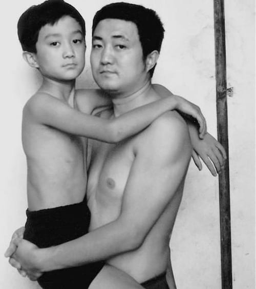 Photo en noir et blanc d'un père et de son fils torse-nu en 1996