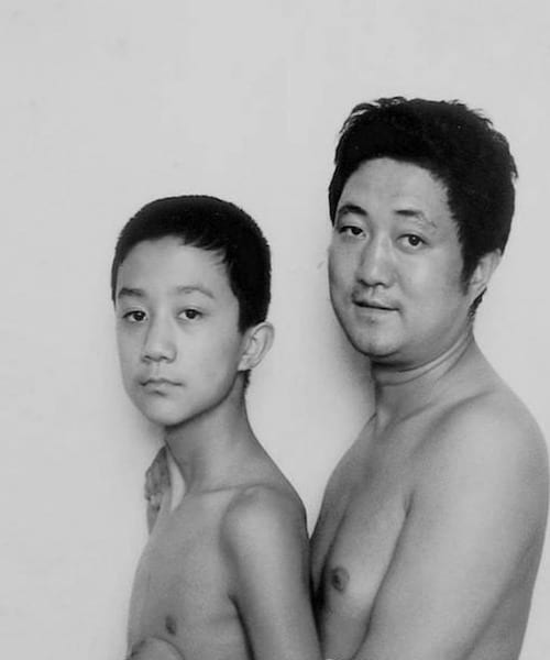 Photo en noir et blanc d'un père et de son fils torse-nu en 1997