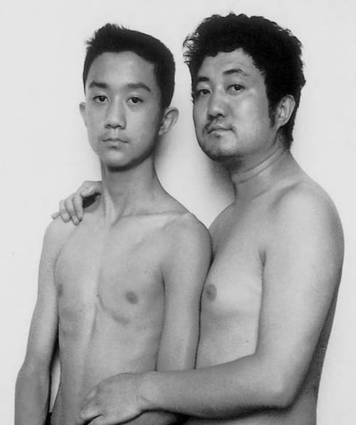 Photo en noir et blanc d'un père et de son fils torse-nu en 1998