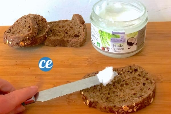 Une tartine de pain avec un couteau qui met de l'huile de coco dessus